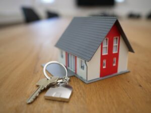 A property manager inspects a clean, well-lit apartment while tenants discuss repairs nearby.